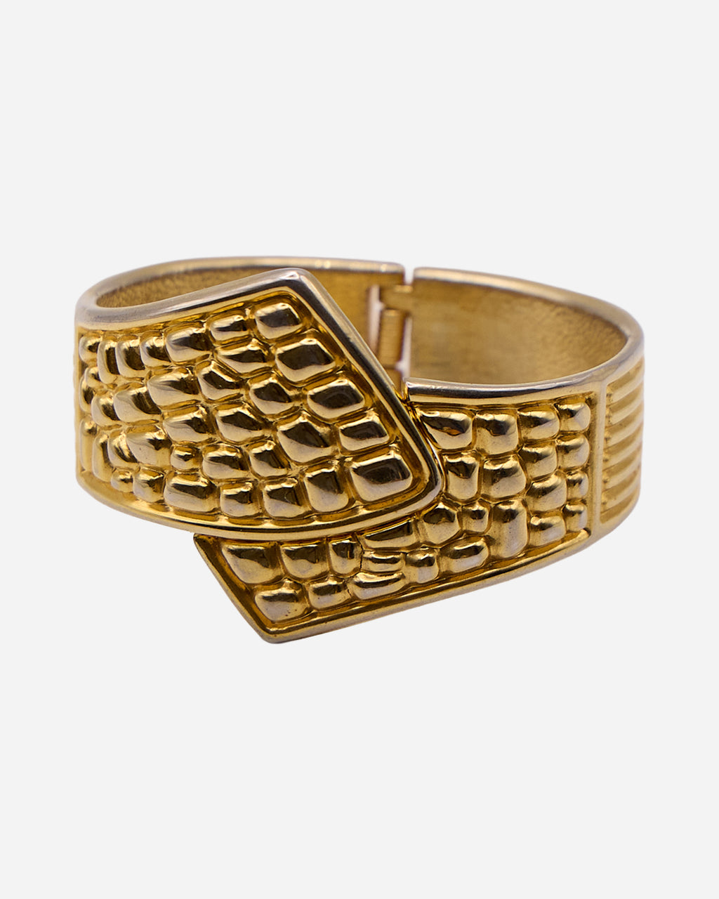 Bracciale vintage rigido dorato con estremità sovrapposte e motivo geometrico a mosaico in rilievo.