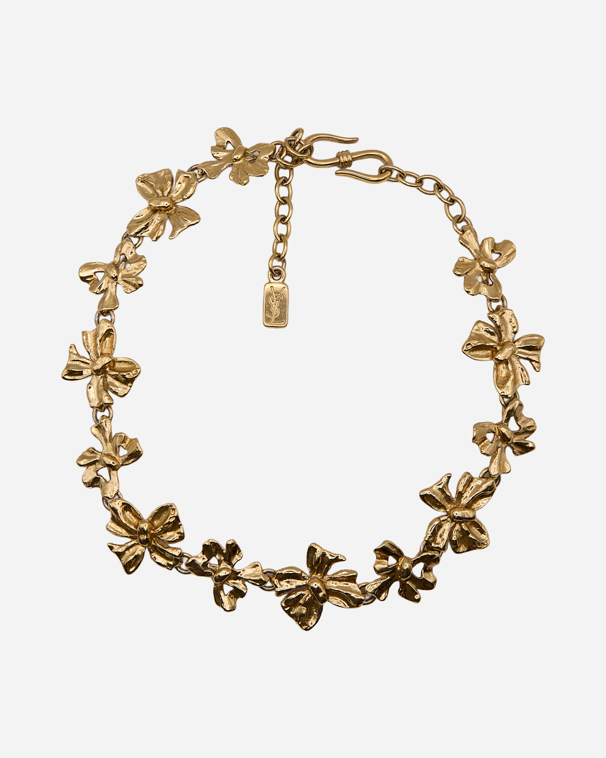 Collana Yves Saint Laurent con fiocchi dorati alternati in due dimensioni, chiusura a S e targhetta YSL.