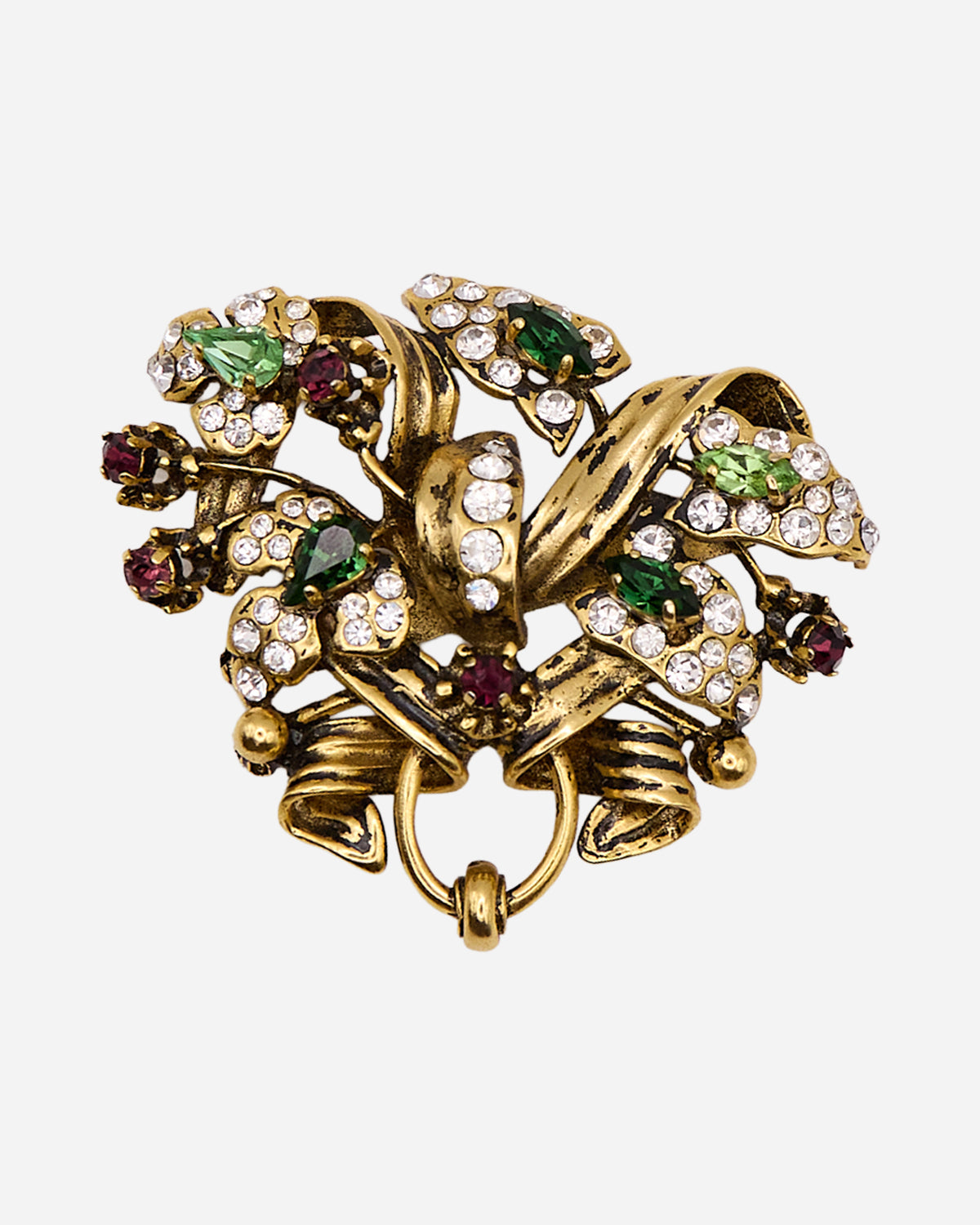 Spilla vintage in metallo dorato con fiori di cristalli verdi e trasparenti, piccoli cristalli viola e nastri ricurvi.
