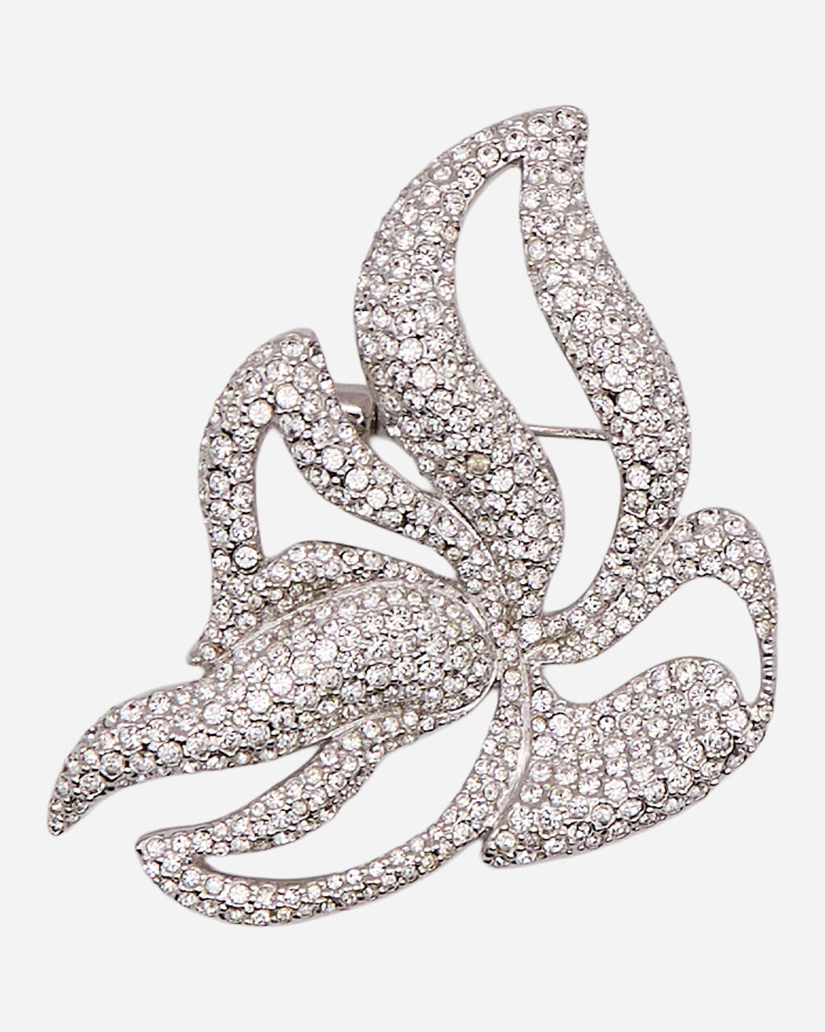 Spilla vintage argentata con foglie stilizzate sinuose, aperture decorative e pavé di cristalli trasparenti.