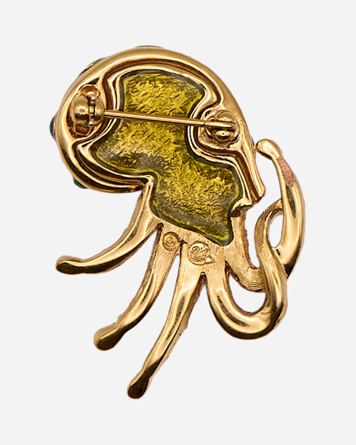 Retro della spilla a nautilus in metallo dorato con chiusura ad ago, fermo di sicurezza e piccolo simbolo impresso.
